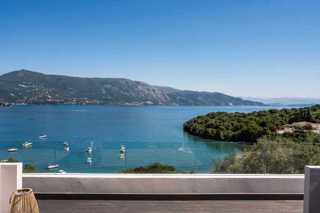 Terrace overlooking a blue bay with moored boats green hills and a clear sky in the background