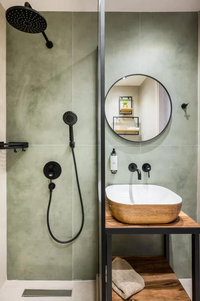 Bathroom with wooden sink cabinet and round mirror at Apovrado Stay